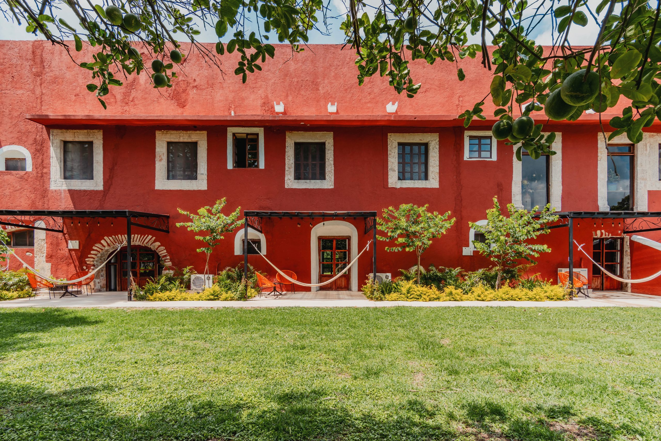 Fachada roja de Hacienda Tepich con jardín amplio